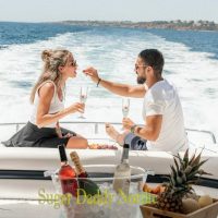 Oletko yhteensopiva sugar daddy tai sugar babe kanssa? Mies antaa naiselle mansikan veneen takaosassa samalla kun he juovat samppanjaa ja ovat onnellisia.