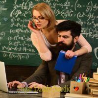 Mitä voit oppia sugar baby? Opi mentoreista Miesmentori istuu pöydän ääressä kirjojen kanssa ja katsoo tietokonetta, samalla kun kaunis silmälasipäinen oppilas halaa häntä takaa ja katsoo tietokonetta.